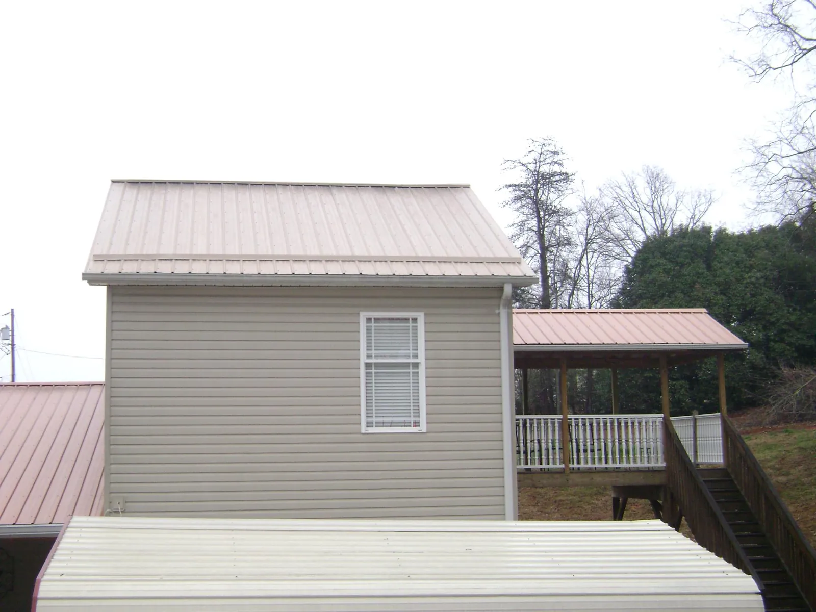 Tan metal roofs on a two story addition and attached porch, from a Roof Replacement job in Eden